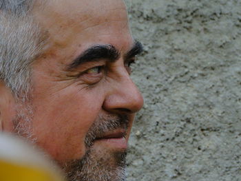 Close-up of mature man looking away by rough wall