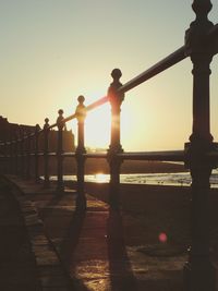 People standing by railing against clear sky during sunset