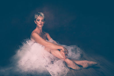 Semi-naked woman wearing tulle tutu against black background