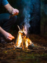 Midsection of man with fire crackers on log