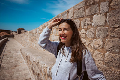 Young woman standing against wall