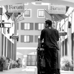 Rear view of man standing against building in city