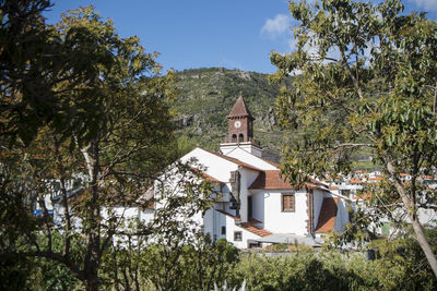 House amidst trees and buildings against sky