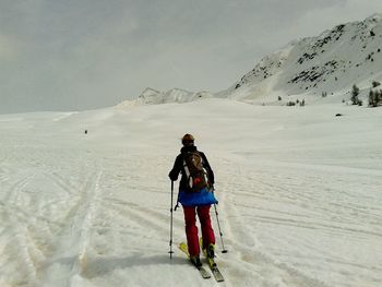 Rear view of man skiing on snowcapped mountain against sky