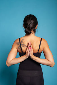 Rear view of woman exercising against blue background