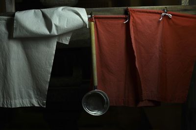 Close-up of kitchen utensil hanging with textile on wall