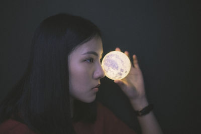 Close-up of young woman holding illuminated crystal ball