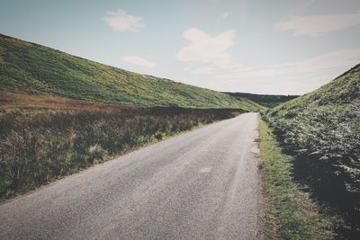 Road amidst field against sky