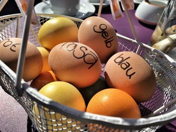 Text on eggs in basket with oranges on table