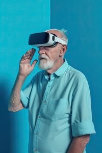 Side view of senior grandfather in virtual headset glasses against blue background. ai generated