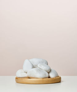 A pile of round white stones on a wooden stand, a stage for displaying products, cosmetics