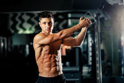 Portrait of shirtless man exercising in gym