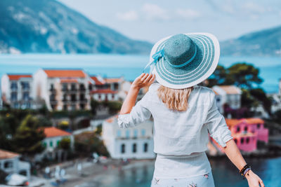 Rear view of woman looking at cityscape against sky