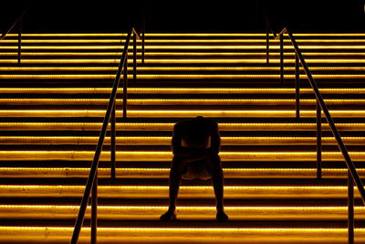 Rear view of man sitting on staircase