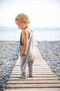 Side view of woman sitting on pier against sea against clear sky