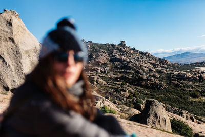 Man on rock by mountains against sky