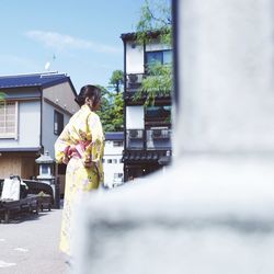 Woman standing by potted plants outside building