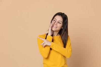 Portrait of smiling young woman against gray background