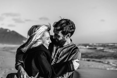 Side view of young couple embracing standing at beach