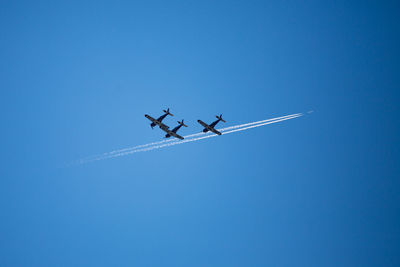 Low angle view of airplane flying against clear blue sky