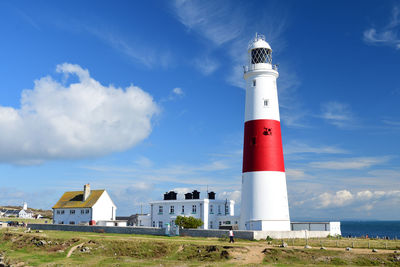 Lighthouse by sea against blue sky