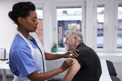 Female doctor vaccinating senior patient