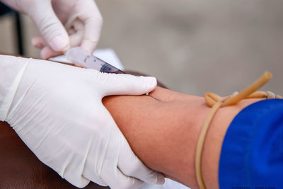 Cropped hand injecting syringe to patient