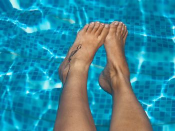 Low section of woman relaxing at swimming pool