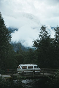 Car on road by trees against sky