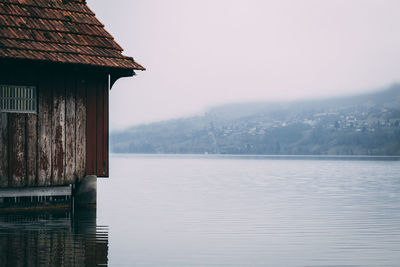 Scenic view of lake by house against sky