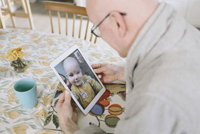 Man having video chat with baby grandson on tablet