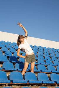 Woman with arms raised against clear blue sky