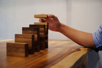 Cropped hand of woman stacking dominoes at table