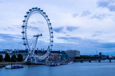 Ferris wheel in city against cloudy sky