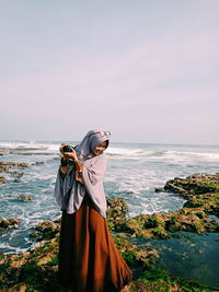 Woman standing at beach against sky