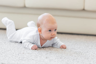 Portrait of cute baby boy on bed at home