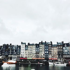 Buildings by river against sky in city