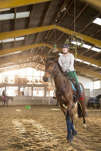 Woman riding horse in stable