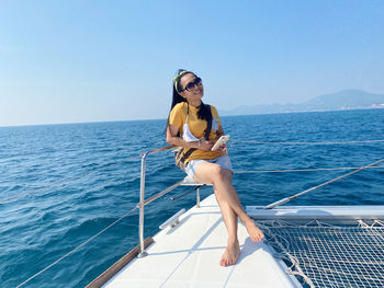 Young woman wearing sunglasses on sea against sky