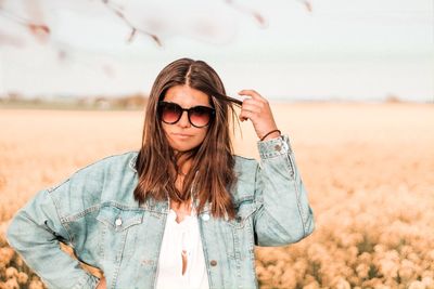 Beautiful young woman wearing sunglasses standing on field