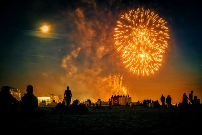 Silhouette people watching fireworks at night