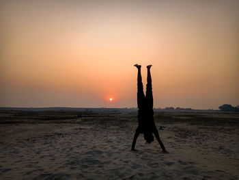 Silhouette man on beach against sky during sunset