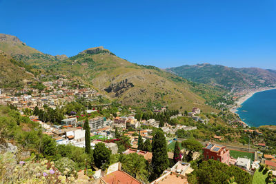 High angle view of townscape and mountains against clear blue sky