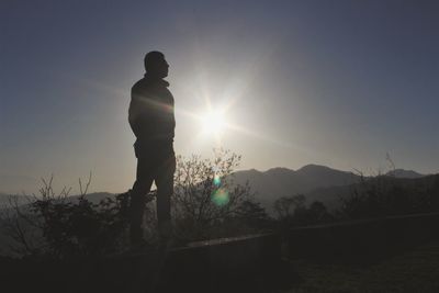 Silhouette man standing on field against sky during sunset