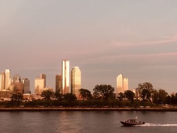 River by modern buildings in city against sky