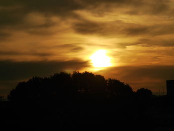 Silhouette trees against dramatic sky during sunset