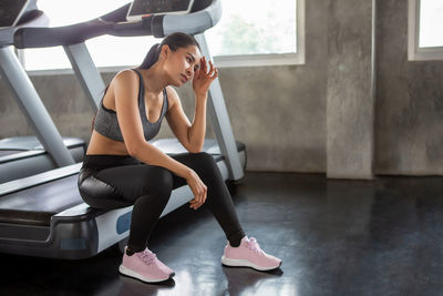 Woman looking away while sitting on floor