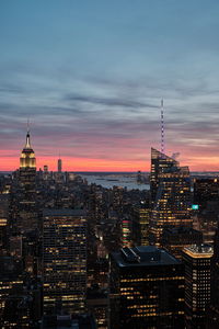 Illuminated buildings in city against sky during sunset