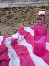 Close-up of red bottle on sand at beach