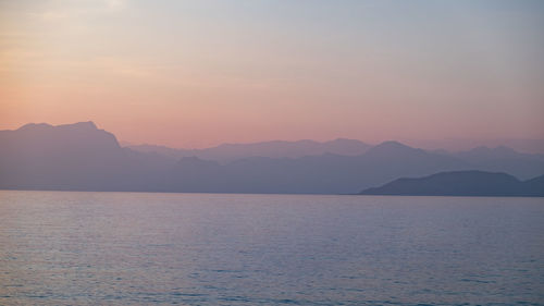 Scenic view of sea and mountains against sky during sunset